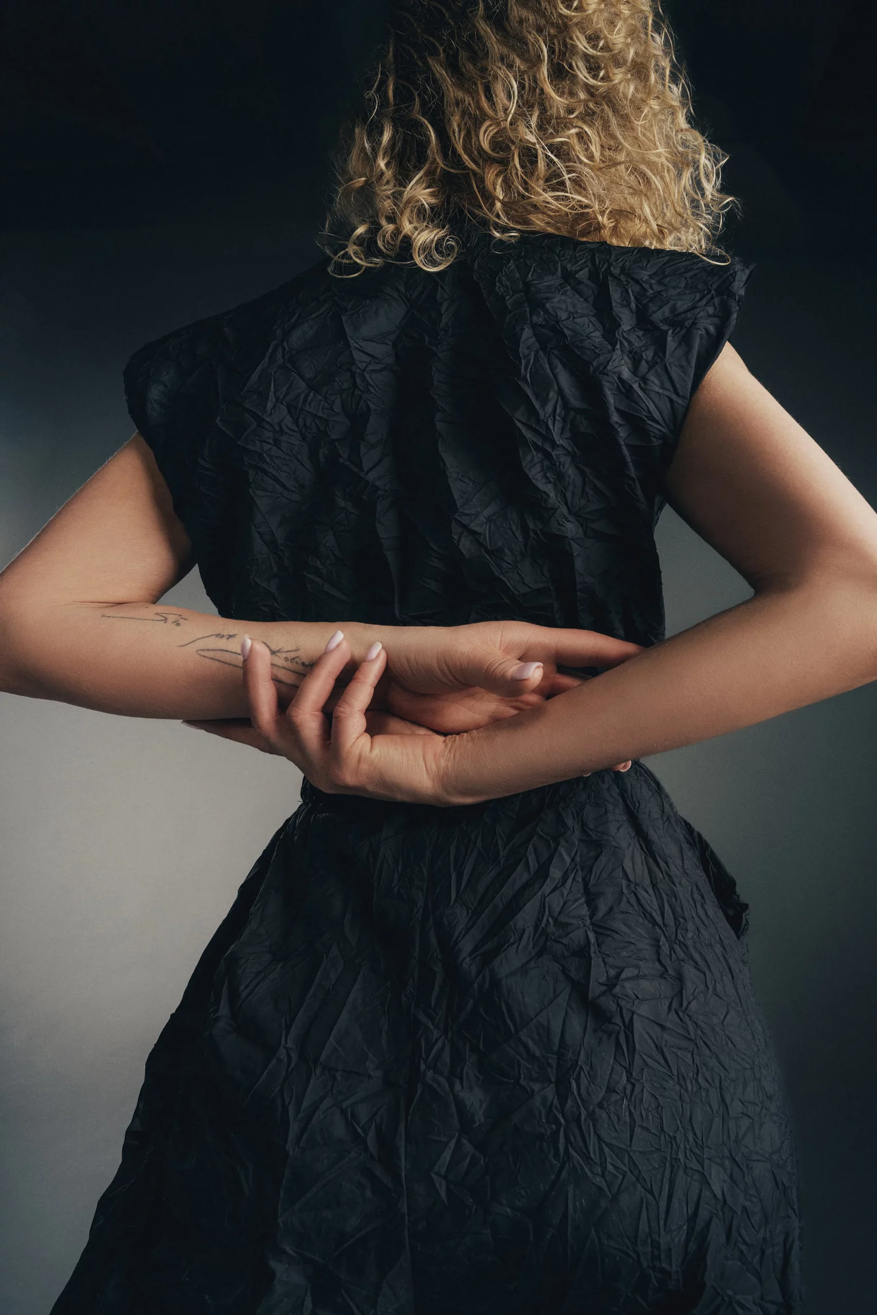 Modelka w czarnym eleganckim kombinezonie bez rękawów z zamkiem i szpilkami – stylowa sesja w studio